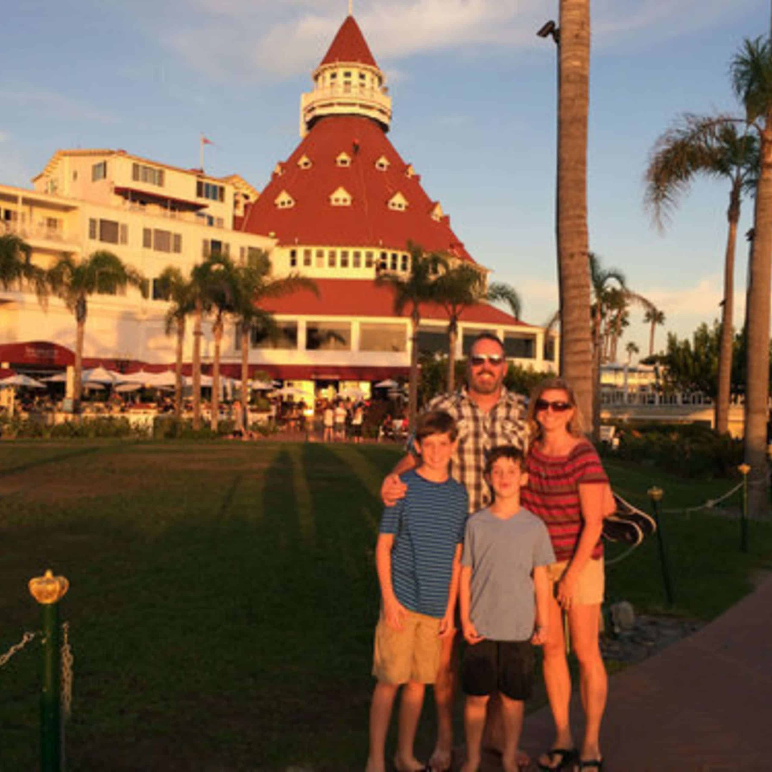 A family is posing in front of a building in front of palm trees.