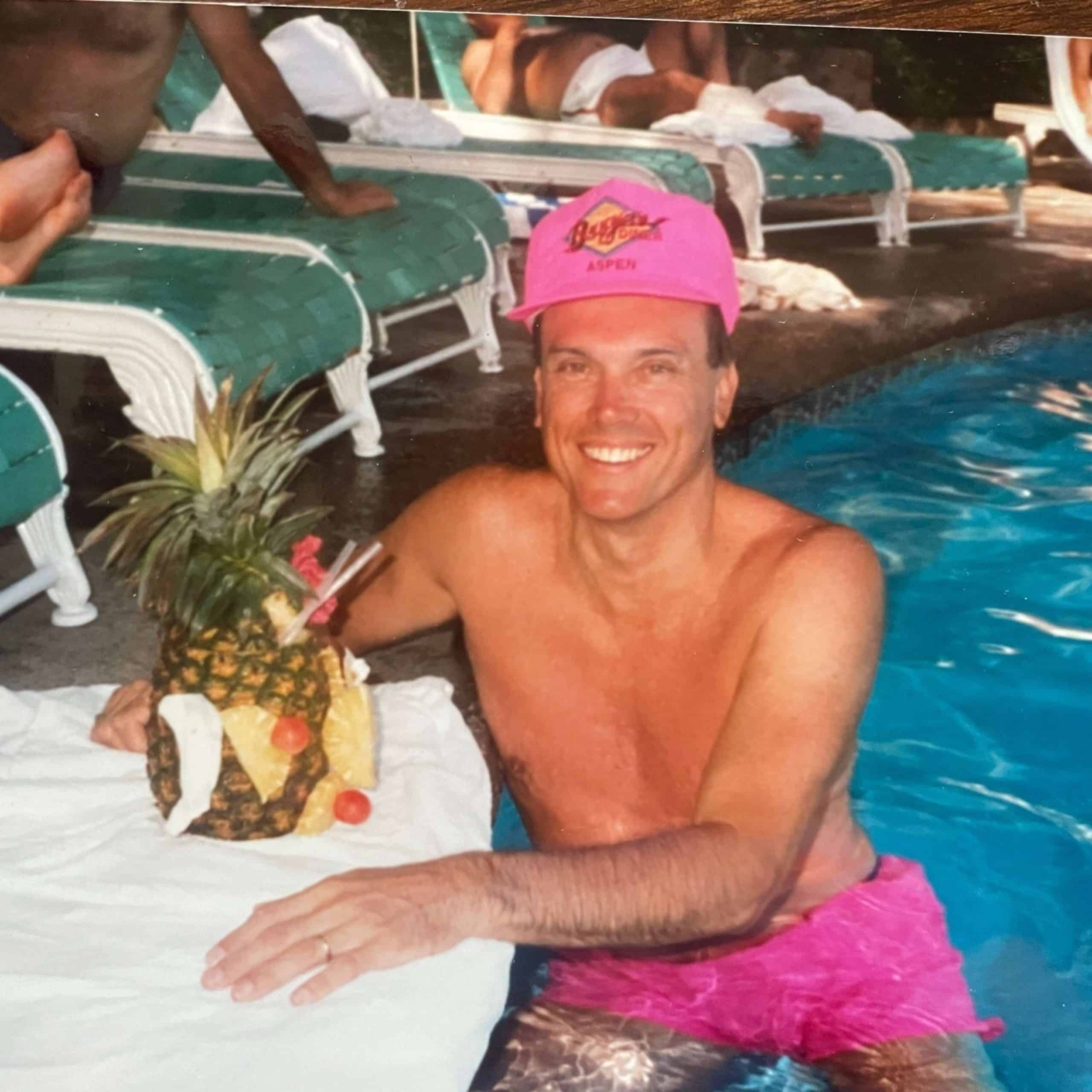 A man in a pink hat with a pineapple in his hand.