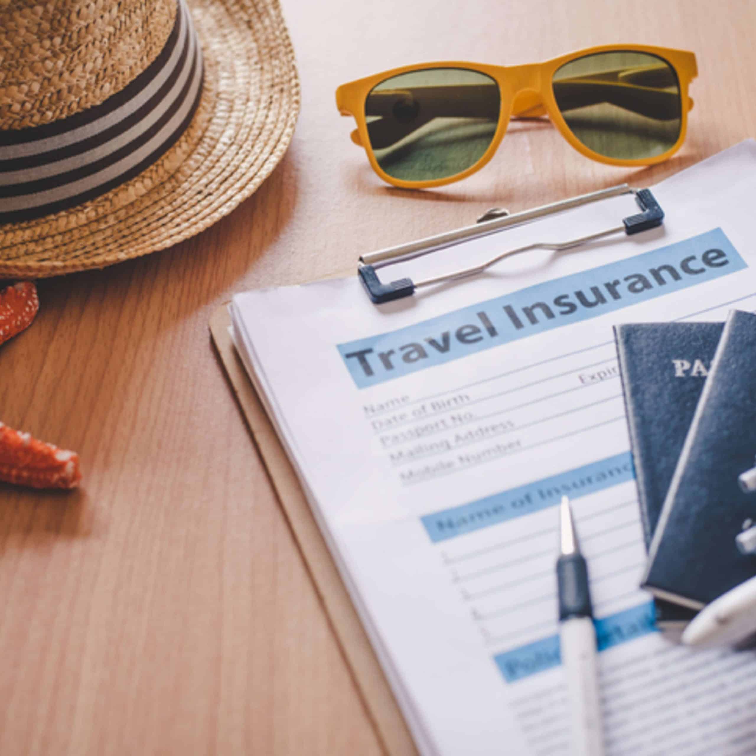 A travel insurance form with a hat and sunglasses on a desk.