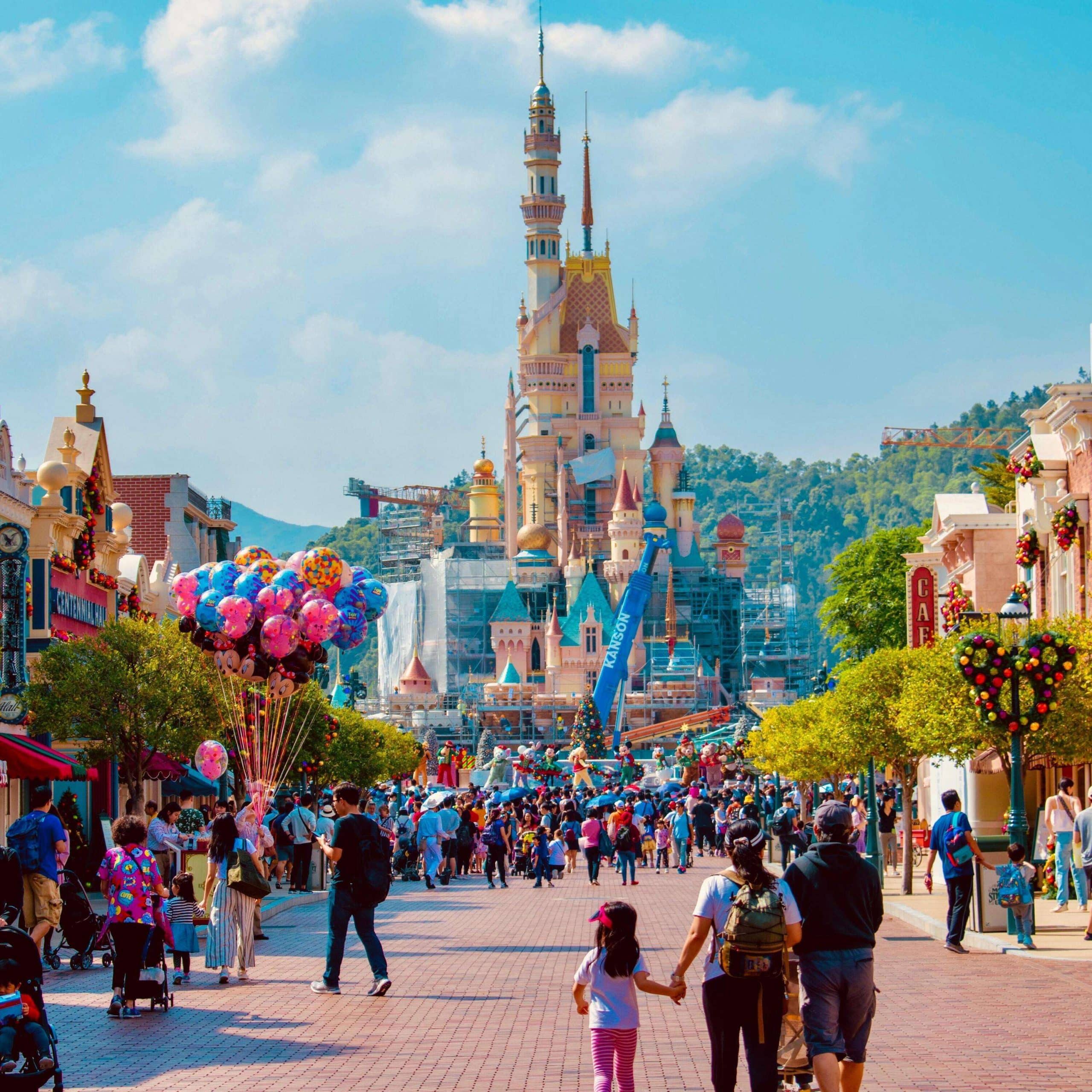 A group of people walking down a street with a castle in the background.