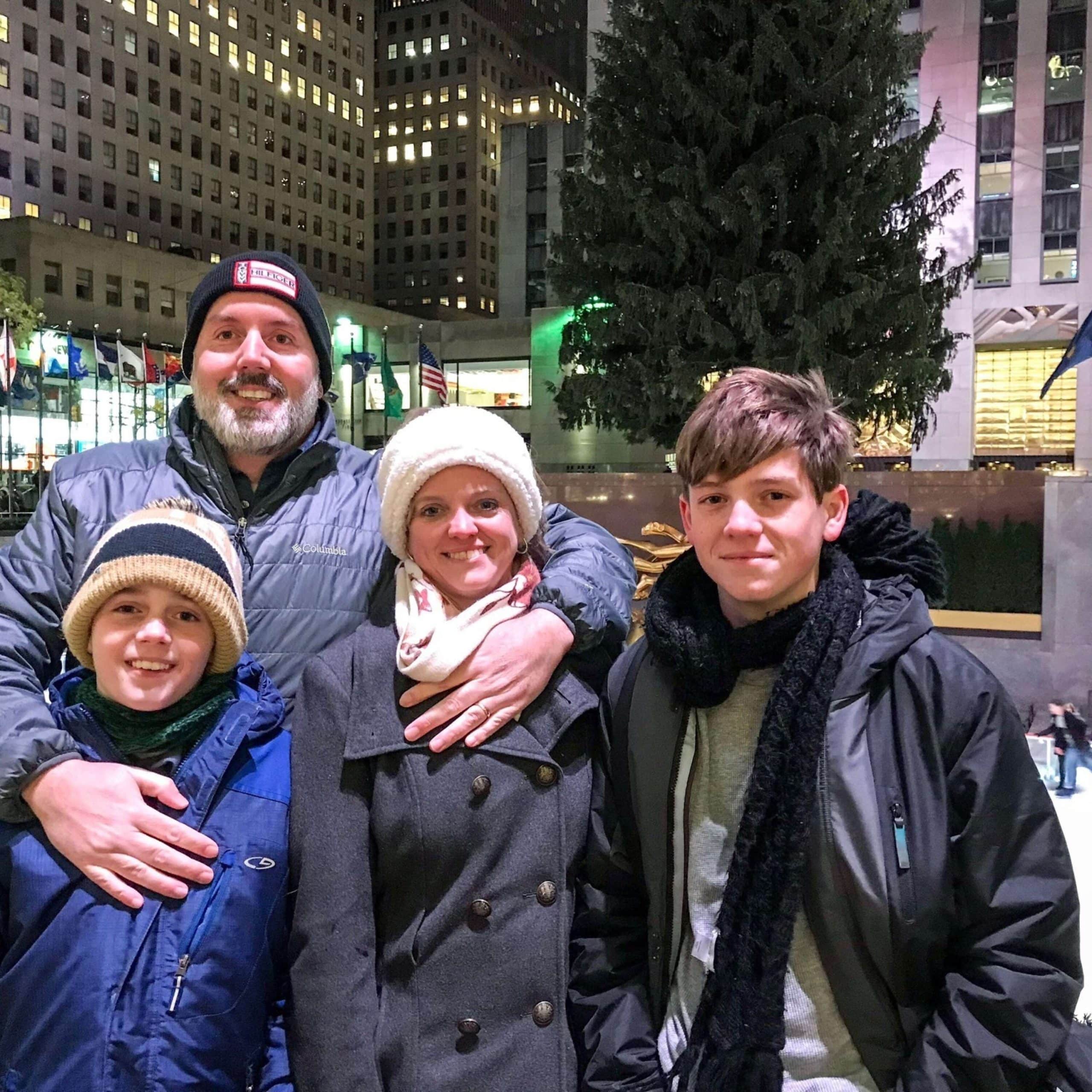 A family posing in front of a christmas tree at rockefeller center.