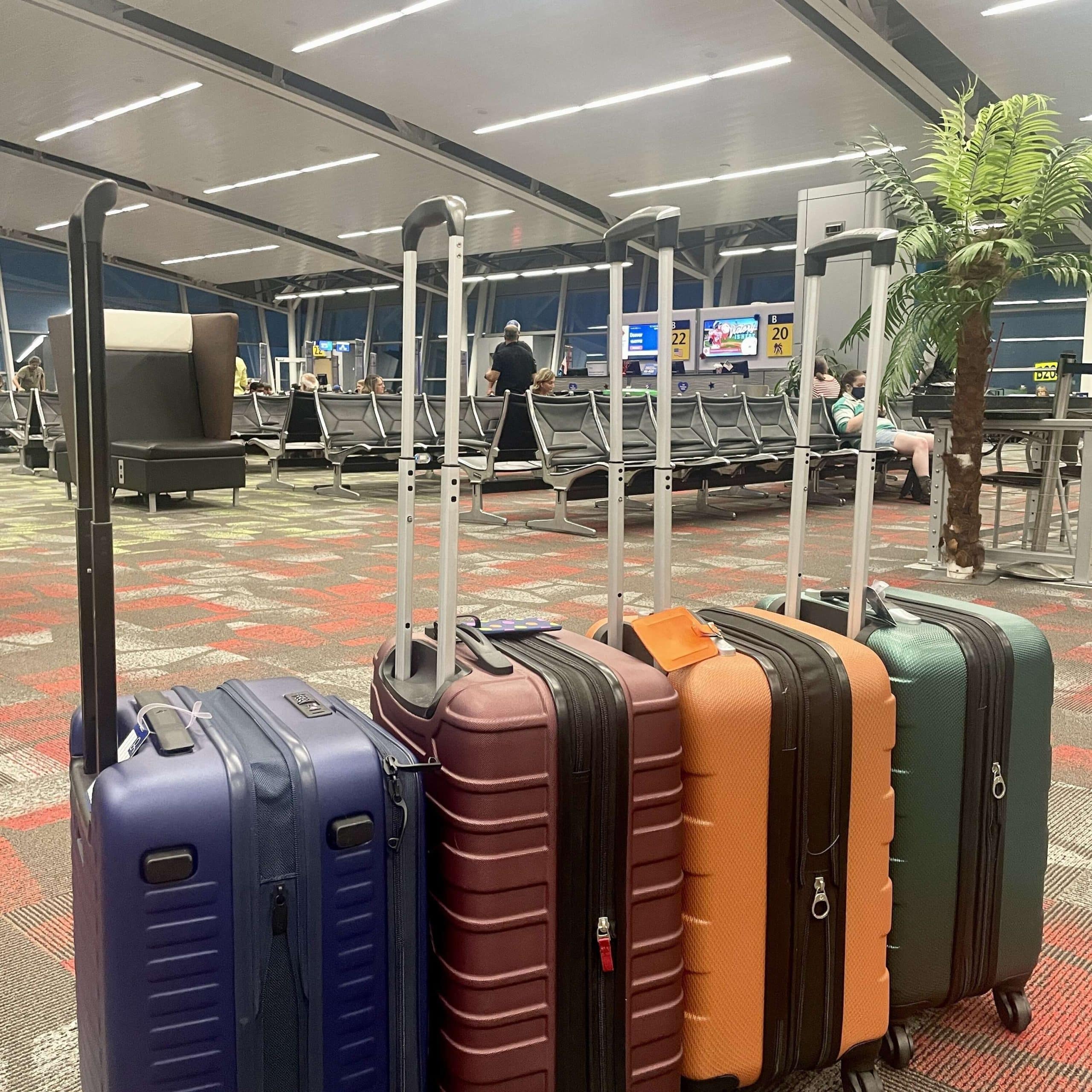 Four pieces of luggage are lined up in an airport.