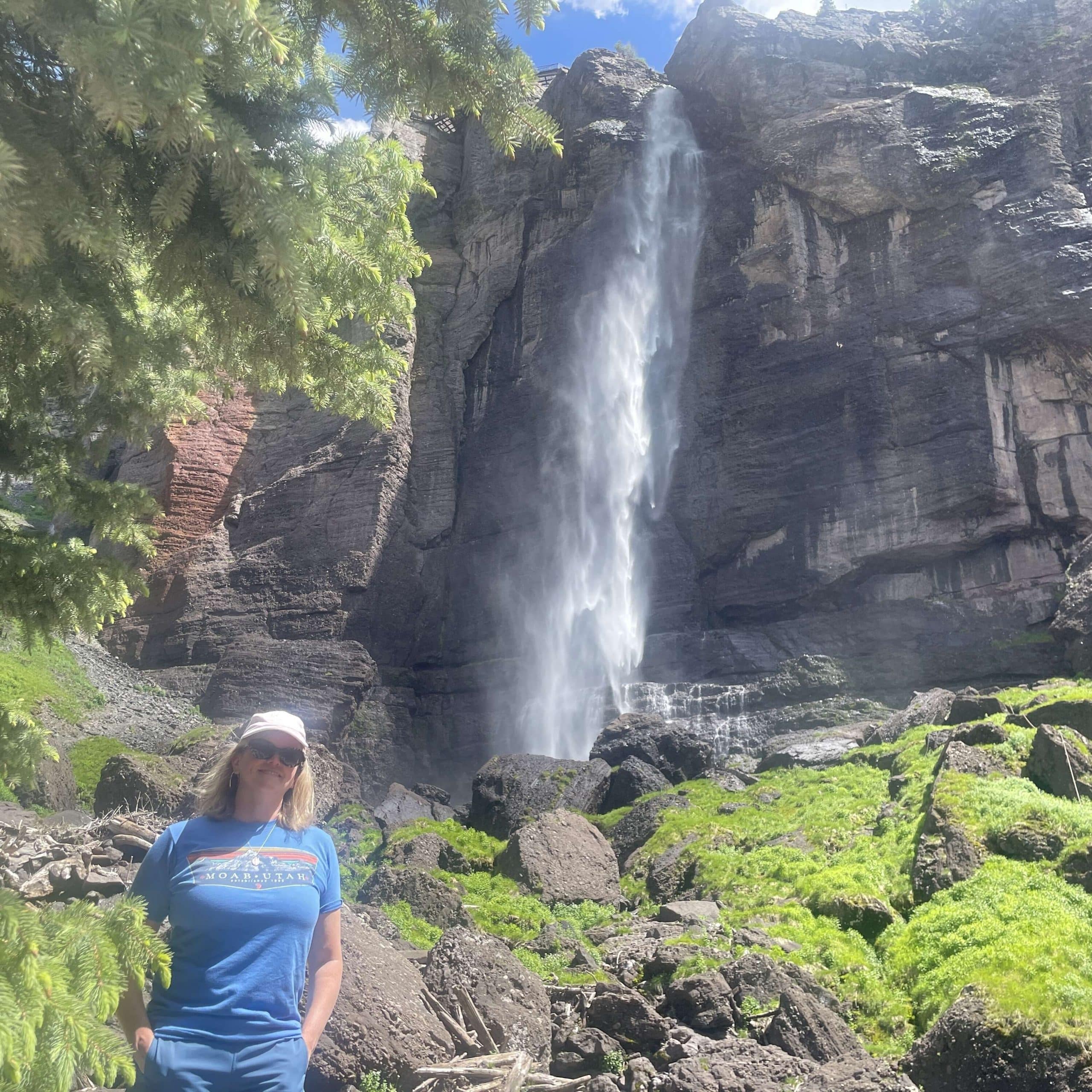 A woman standing in front of a waterfall.