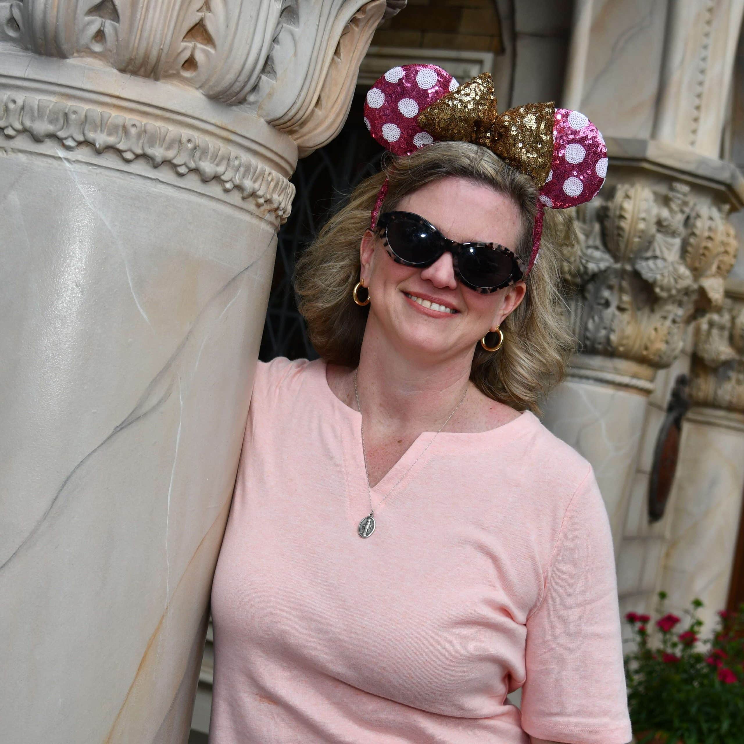 A woman wearing sunglasses and a mickey mouse ear hat.