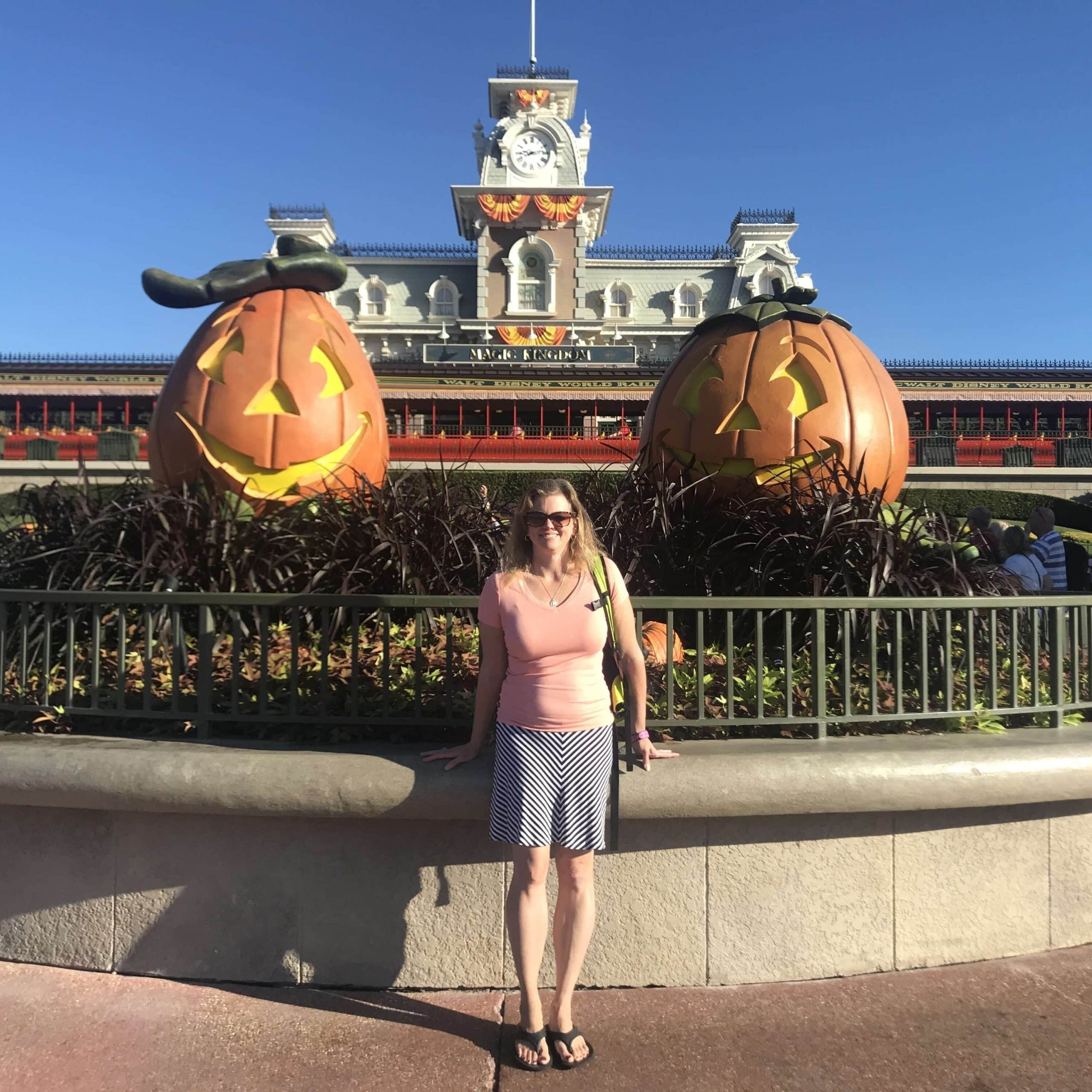 A woman standing in front of two pumpkins in front of the castle.