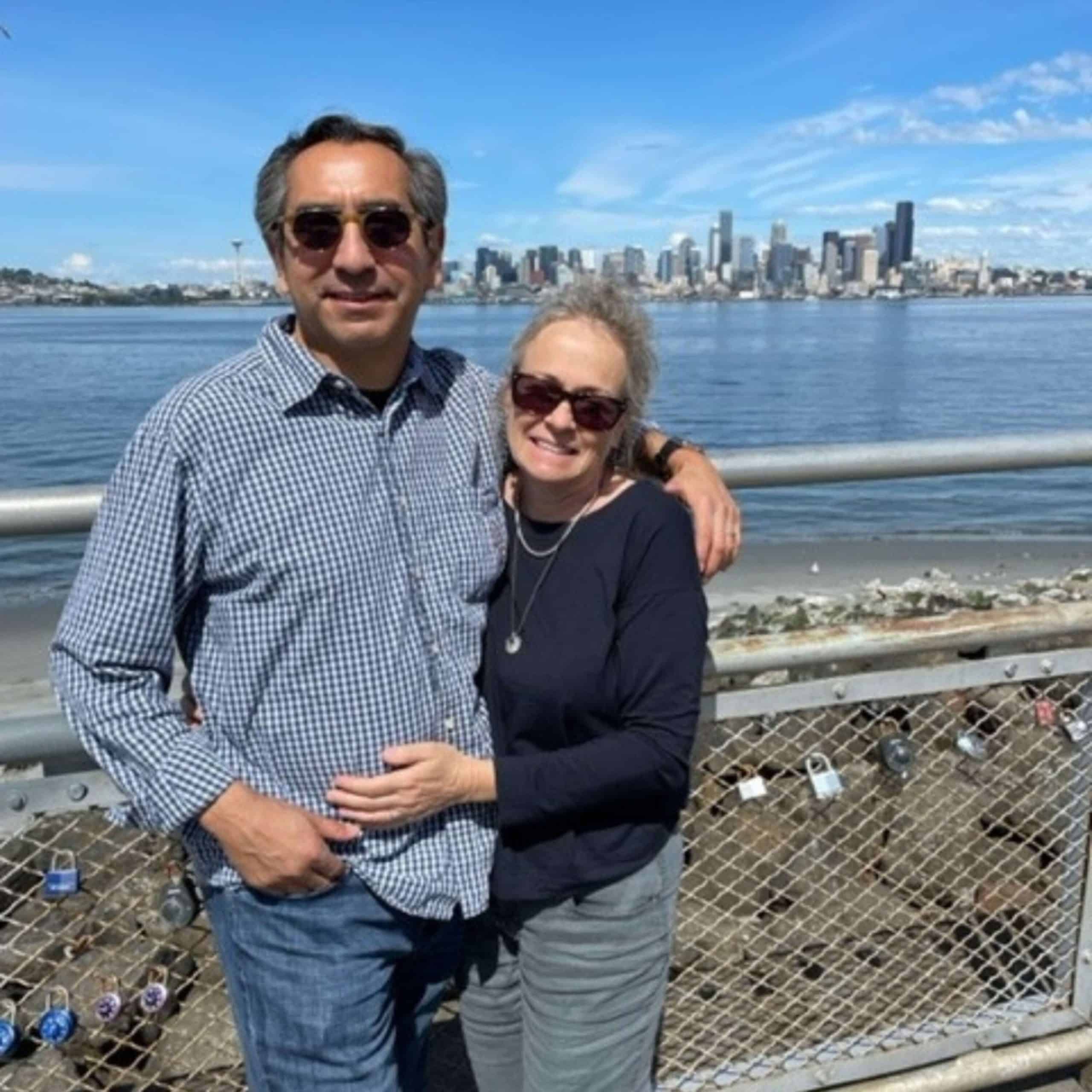 A man and woman posing for a photo with the seattle skyline in the background.