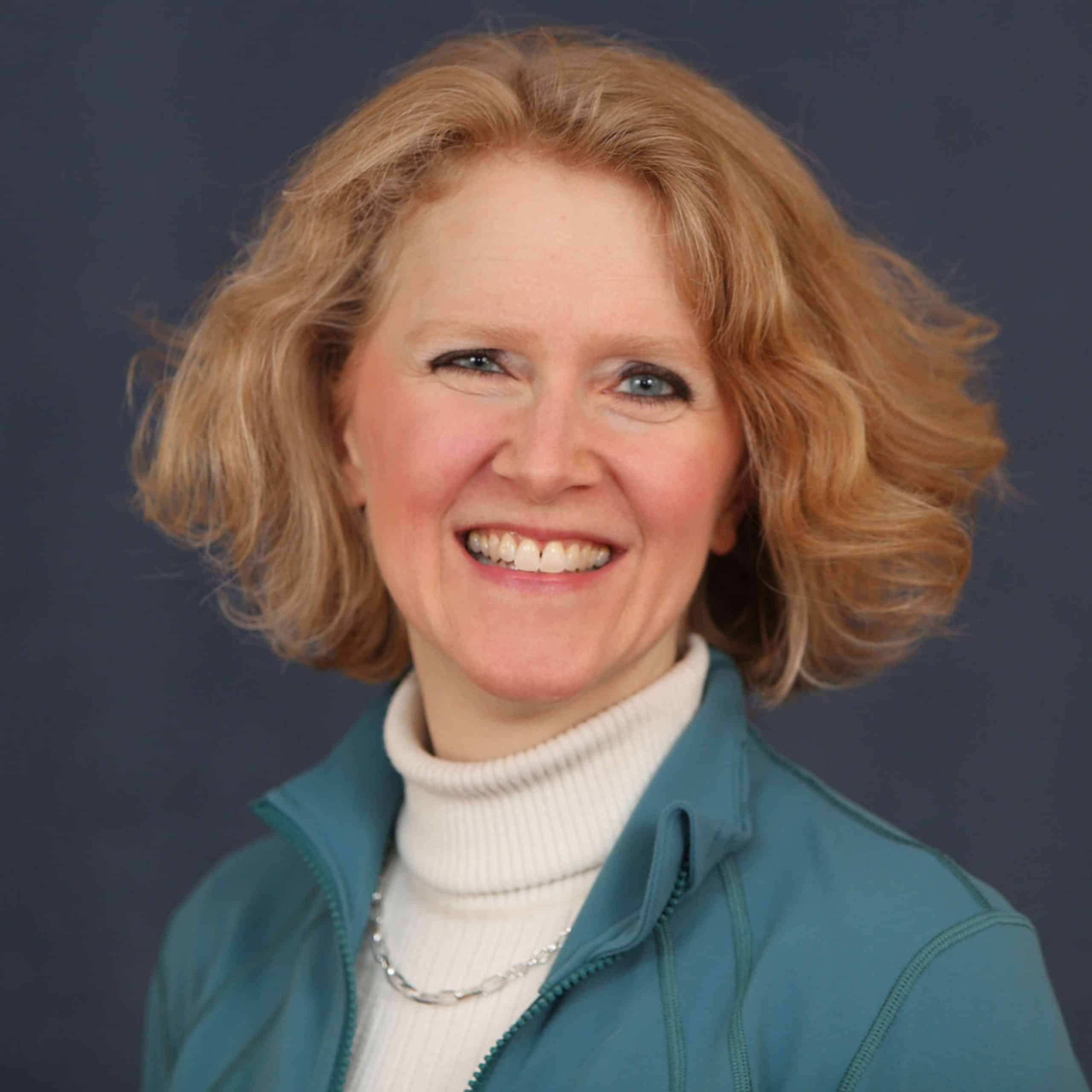 A smiling woman in a blue jacket.