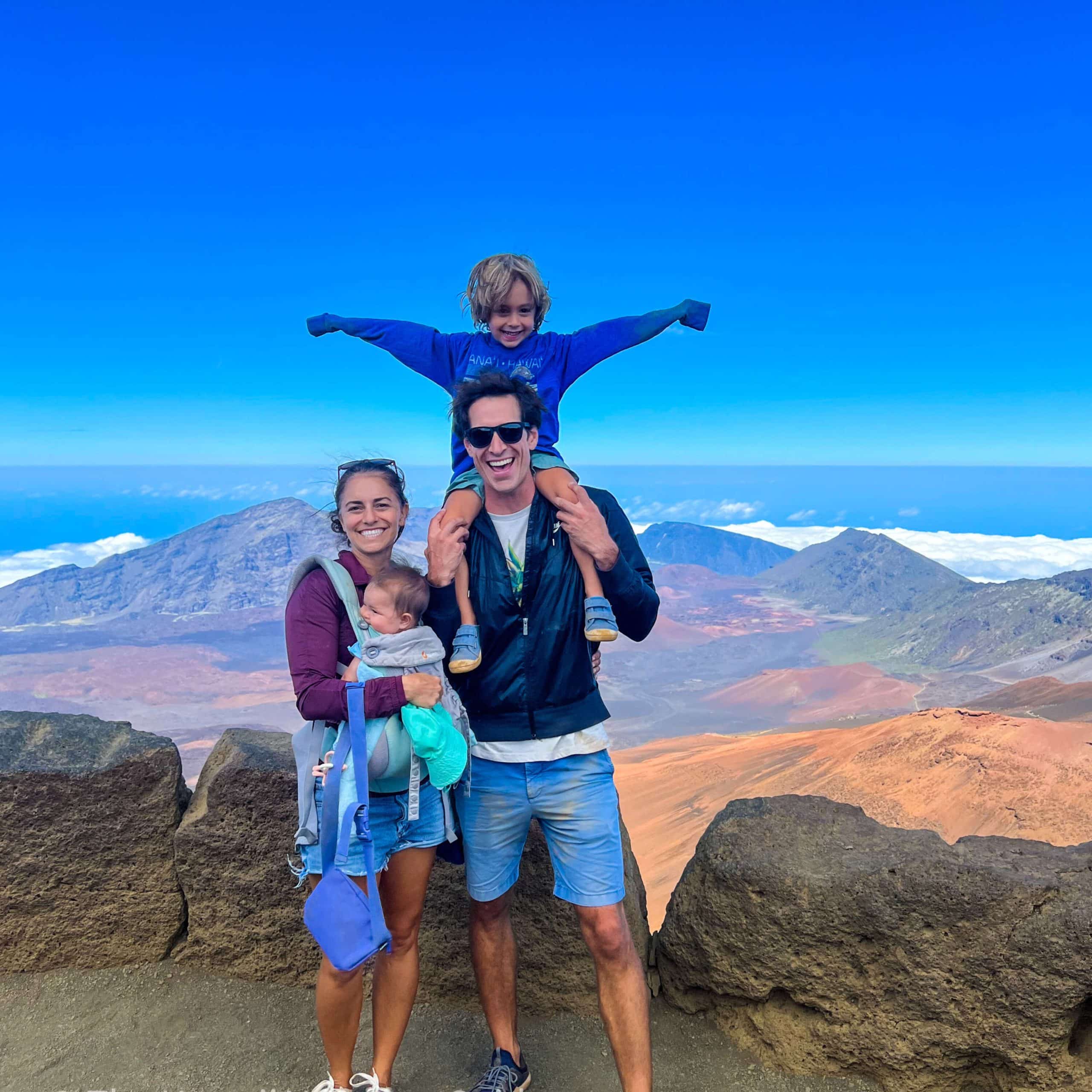 A family poses for a picture at the top of a mountain.