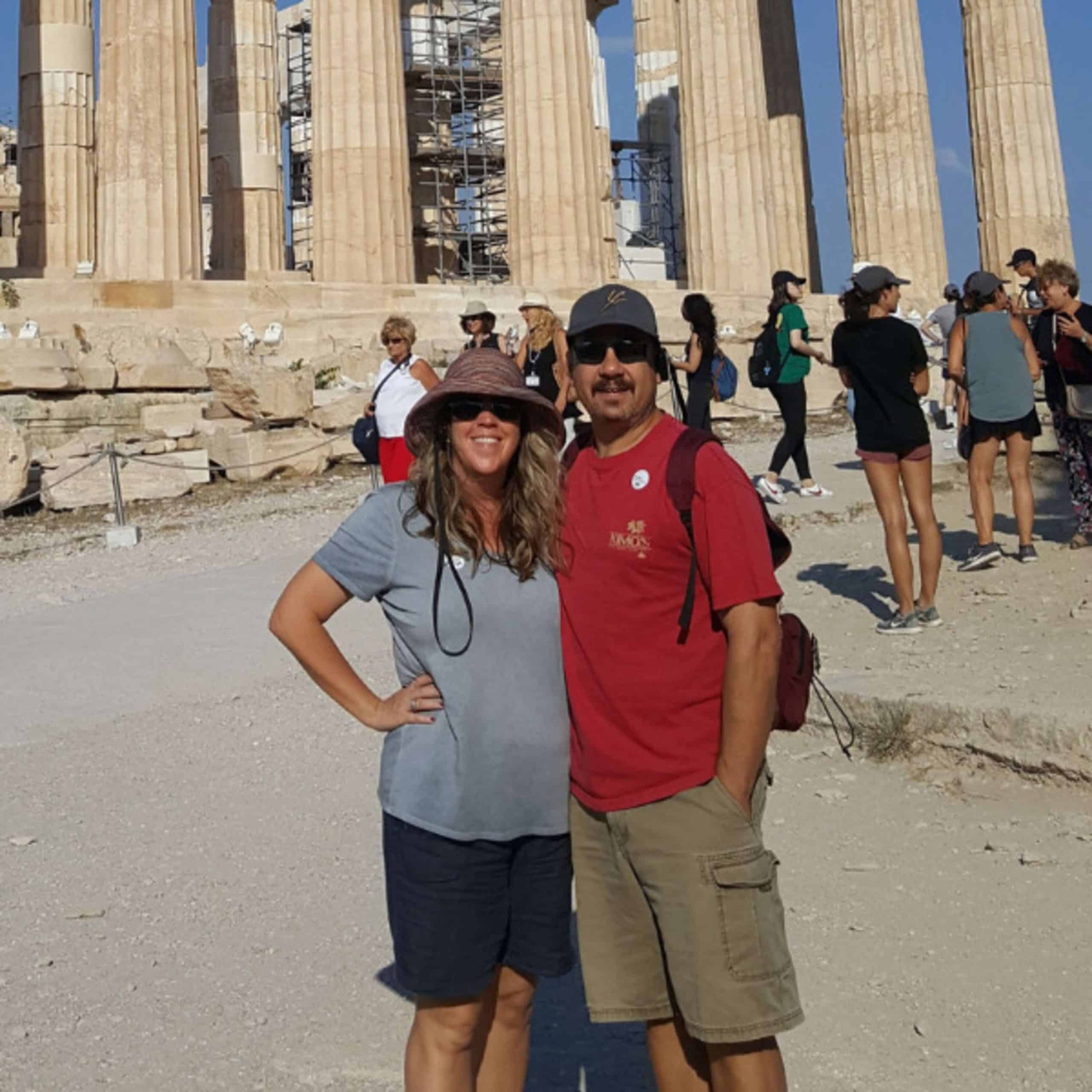 A man and woman posing in front of the parthenon.