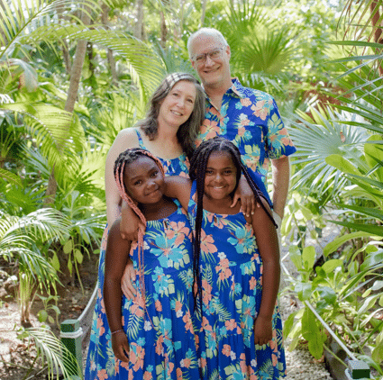 A family posing for a picture in a tropical garden.