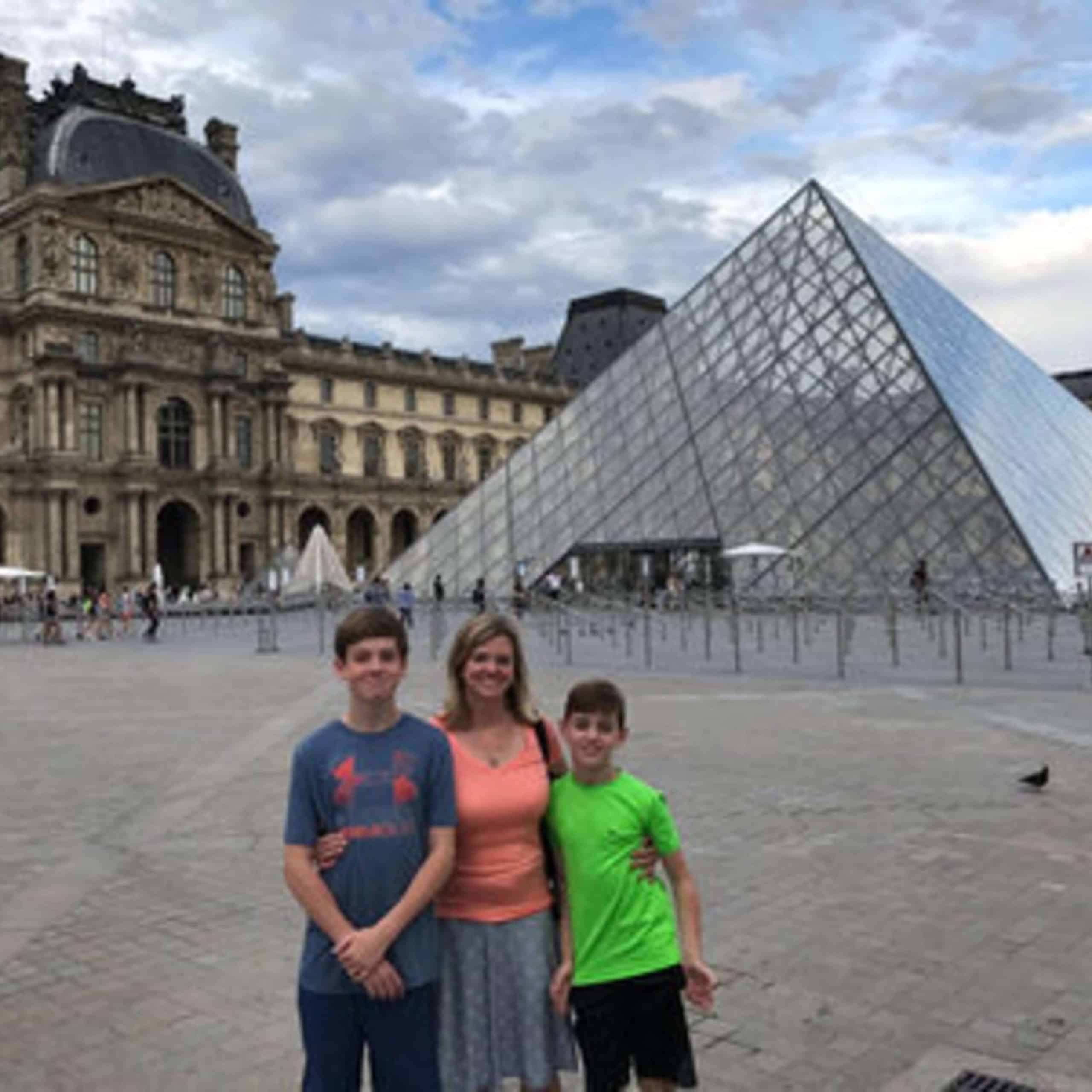 A family poses in front of the louvre pyramid.