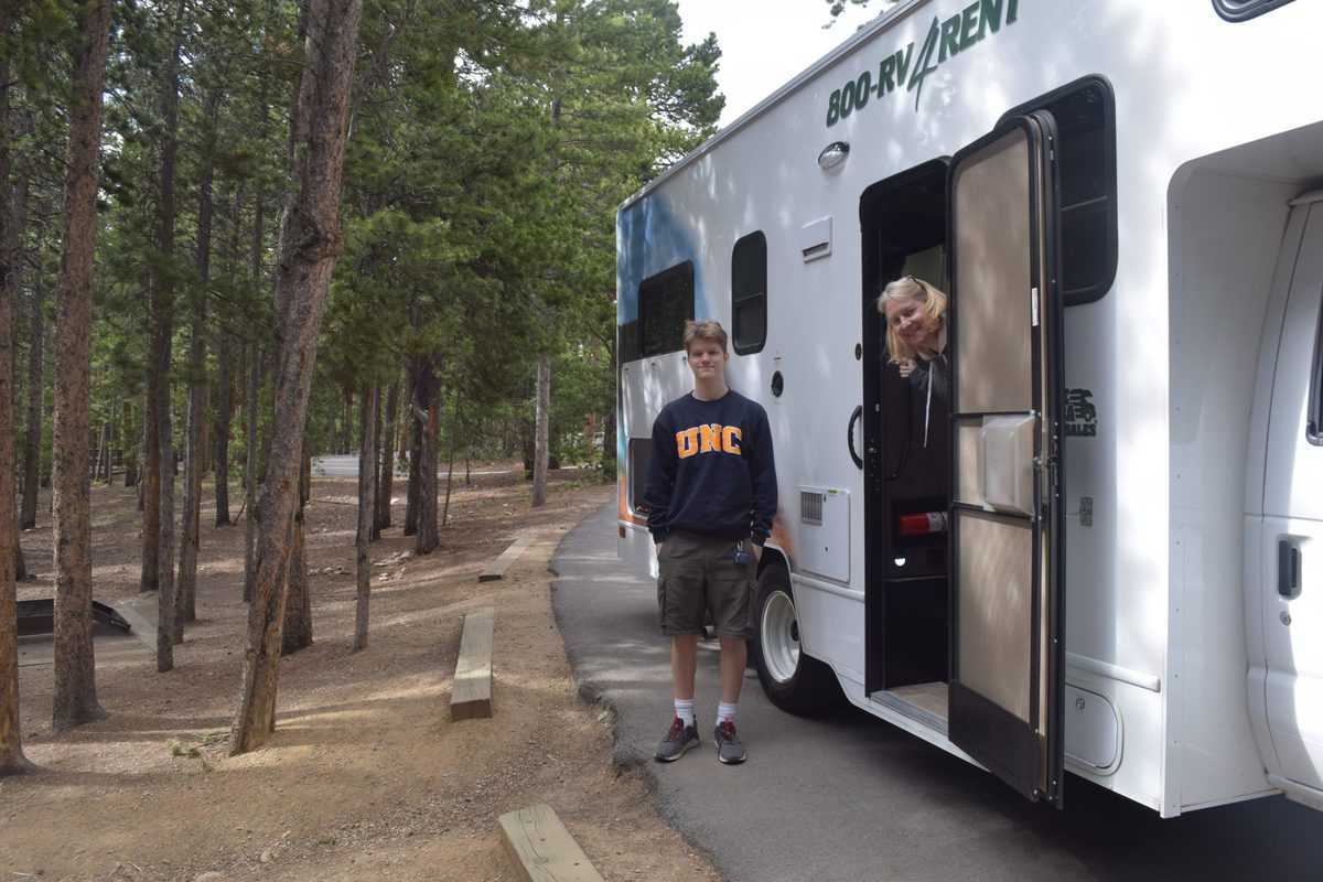 Two people embracing adventure while standing in front of a white RV.