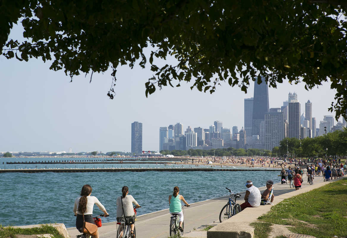 A group of people enjoying biking along a Chicago waterfront.