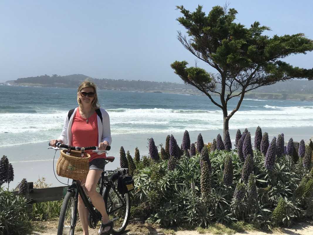 A woman on a bicycle next to the ocean.