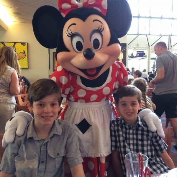 Two boys posing for a photo at a Disney restaurant with Minnie Mouse.