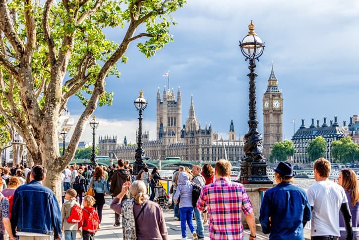 A group of people walking along a river in london.