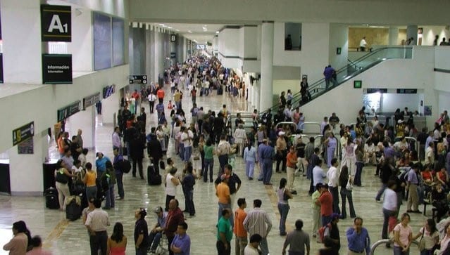 A crowd of people walking through an airport.