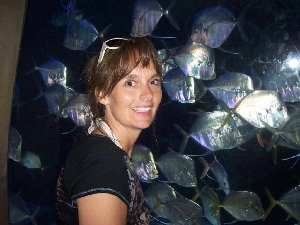 A woman smiling at a fish tank in Atlantis, Paradise Island in Nassau Bahamas