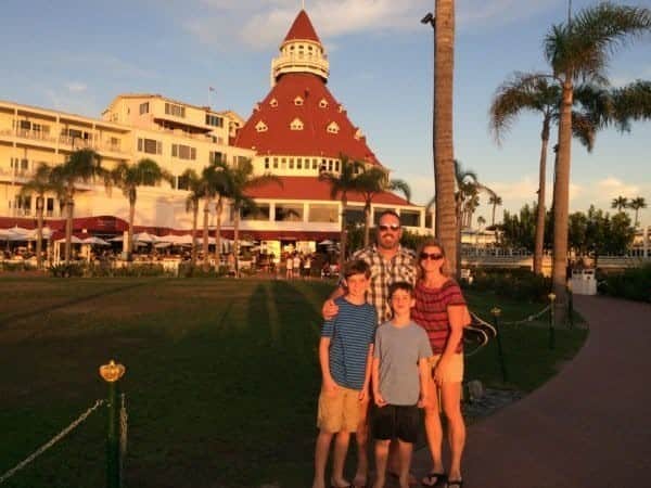 A family is posing in front of a building with palm trees.