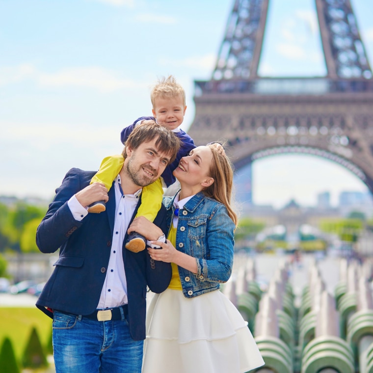 A family is posing in front of the eiffel tower.