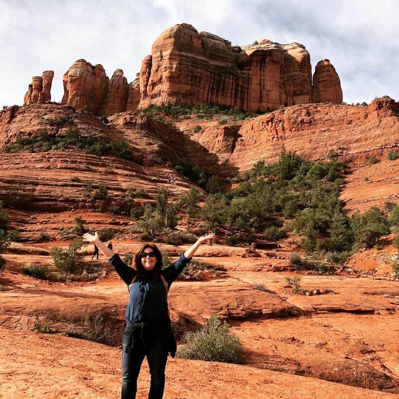 A woman standing in front of red rocks in sedona, arizona.