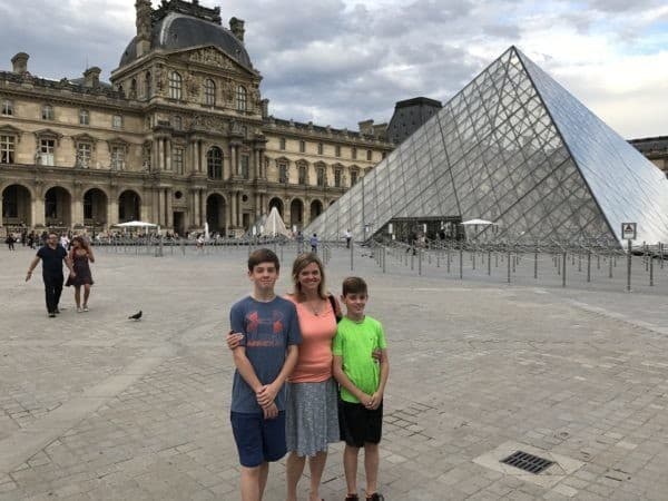 Three people standing in front of the louvre pyramid.