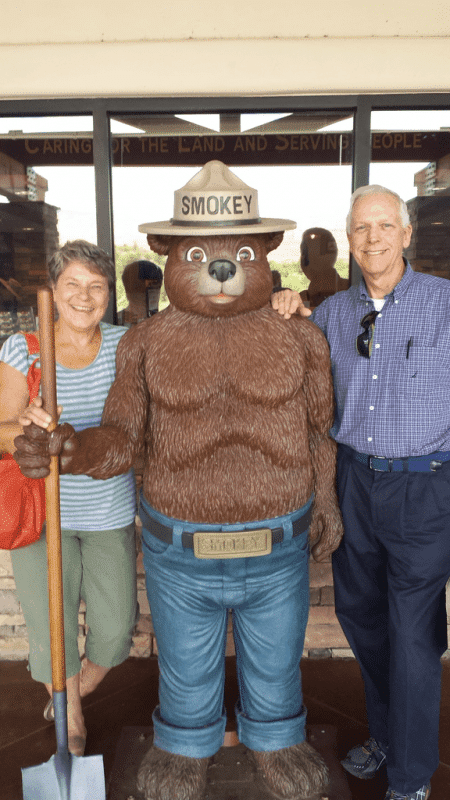 Two people standing next to a statue of a bear.