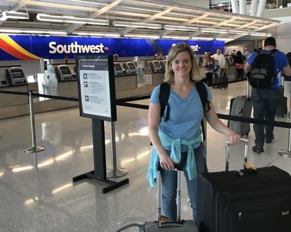 A woman standing with her luggage at an airport.