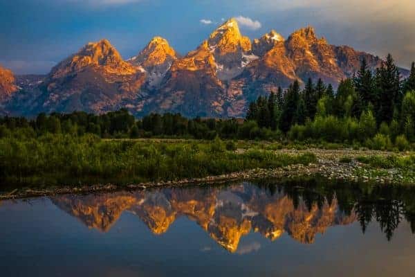 The Grand Teton mountains are reflected in a river within Grand Teton National Park.