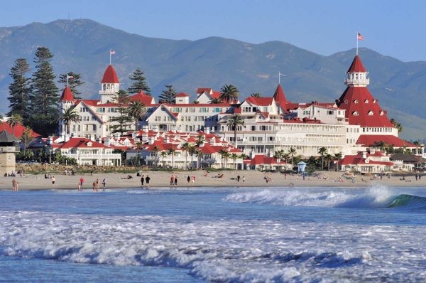 A red and white building on the beach with mountains in the background.