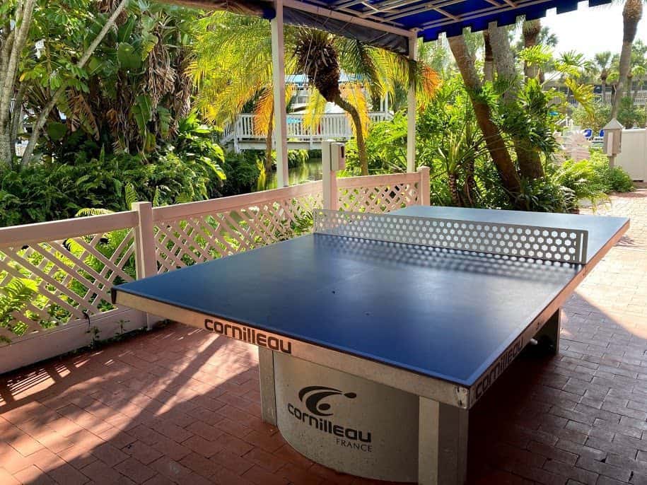 A ping pong table on the patio of Tradewinds Island Grand Resort with palm trees.