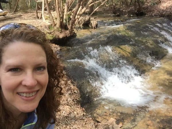 A woman is taking a selfie in front of a stream.