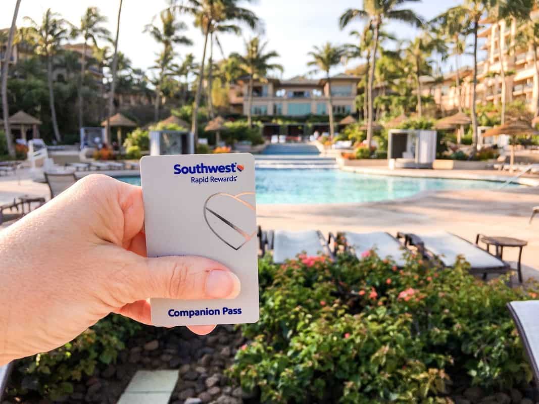 A person holding up a credit card in front of a pool.