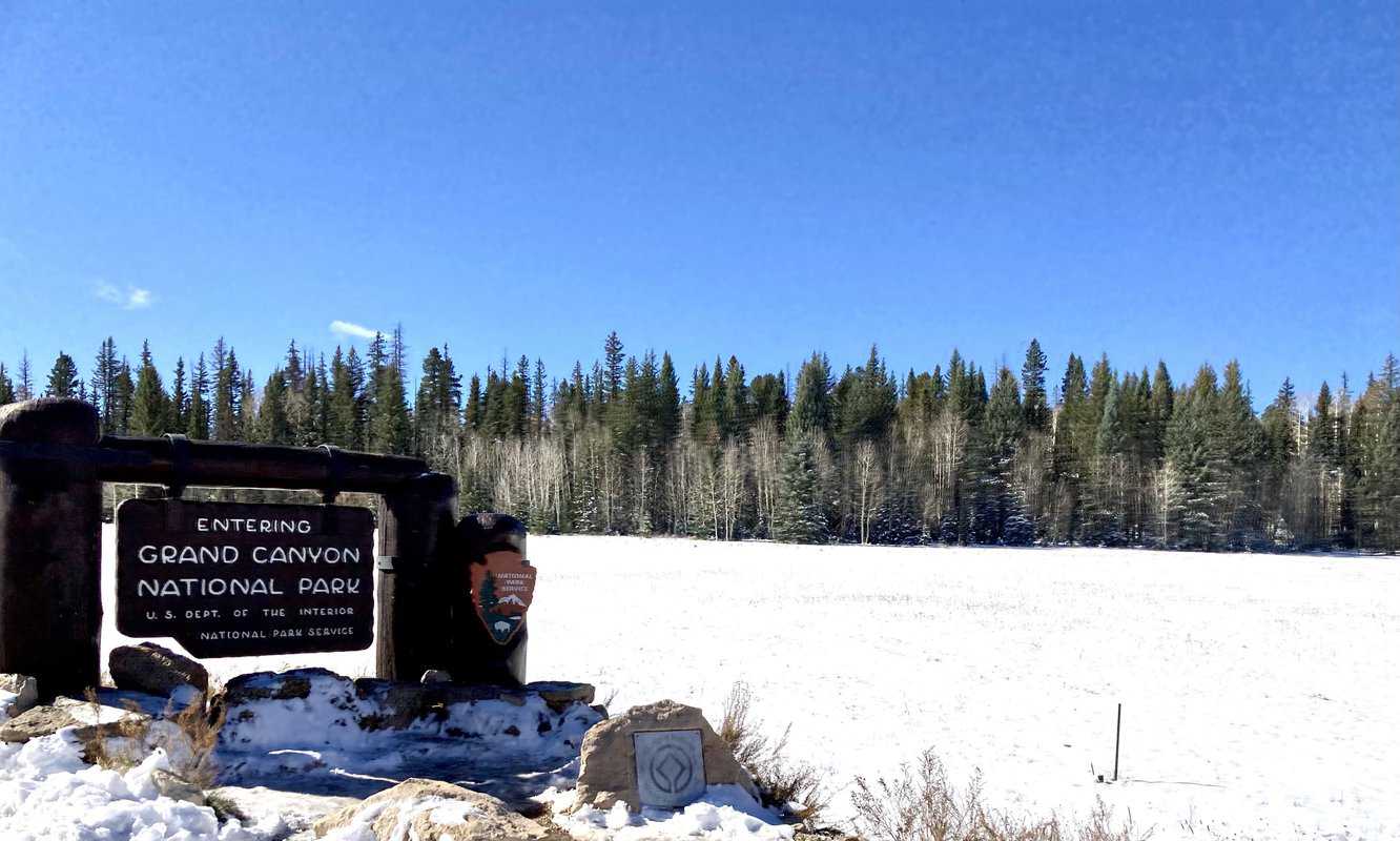 Grand canyon north rim entrance sign in snow. Sign says Entering Grand Canyon National Park.