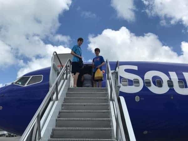 Two people standing on the steps of a blue and white plane.