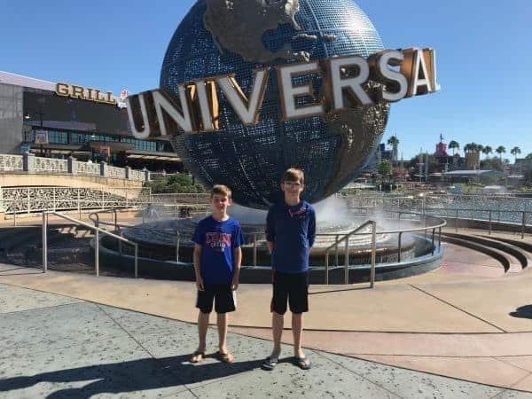 Two boys standing in front of the universal sign.