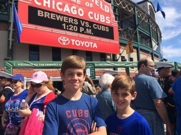 Two boys standing in front of a chicago cubs stadium.