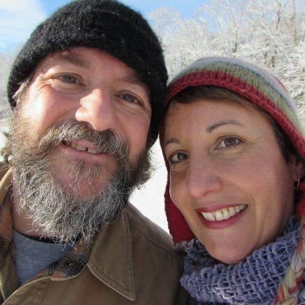 A man and woman smiling for a photo in the snow.