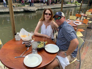 A man and woman sitting at a table next to a river.