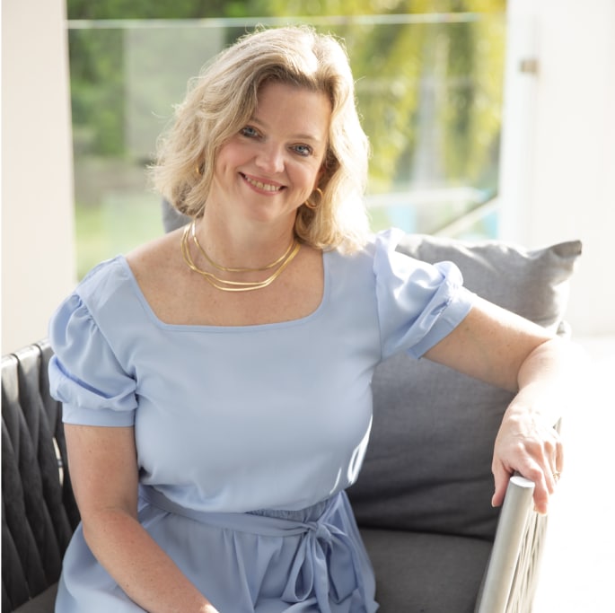 A woman in a blue dress sitting on a couch.