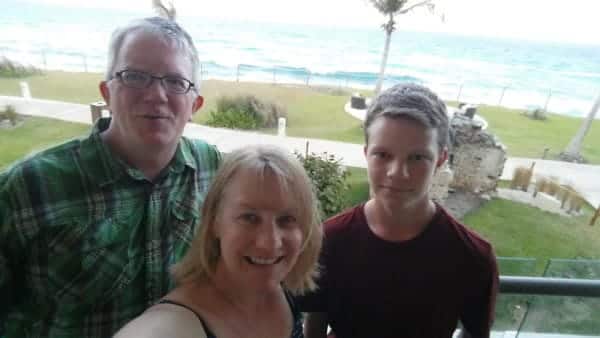 A family is taking a selfie on the balcony overlooking the ocean.