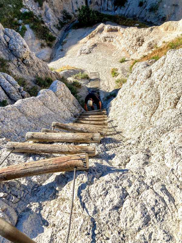 Ladder going up rocks with person climbing up - on Notch Trail, Badlands National Park