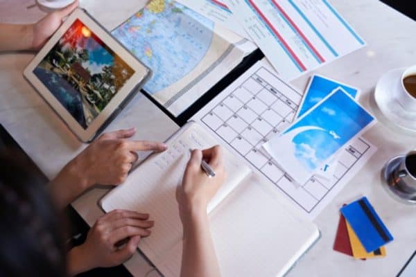 A group of people sitting at a table with a notebook and a tablet.