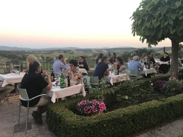 A group of people sitting at tables in a garden.