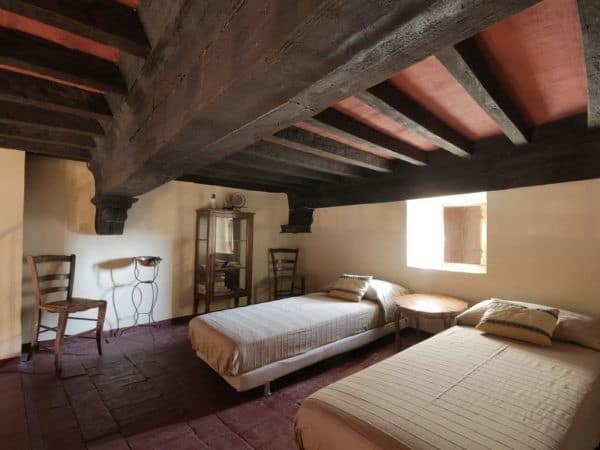 Two beds in a room with wooden beams.