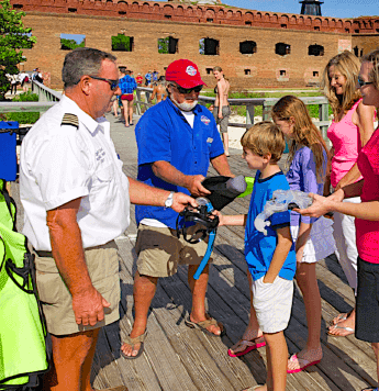 Family receiving snorkel gear from rangers on dock at entrance to Dry Tortugas National Park. Fort Jefferson in background.