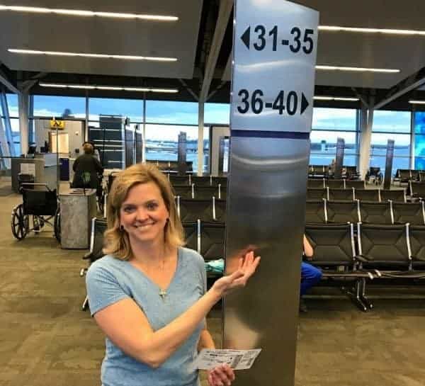 A woman standing next to a sign at an airport.