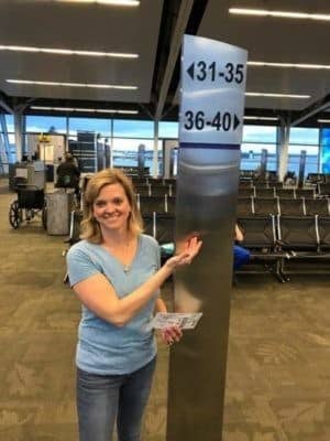 A woman standing next to a sign at an airport.