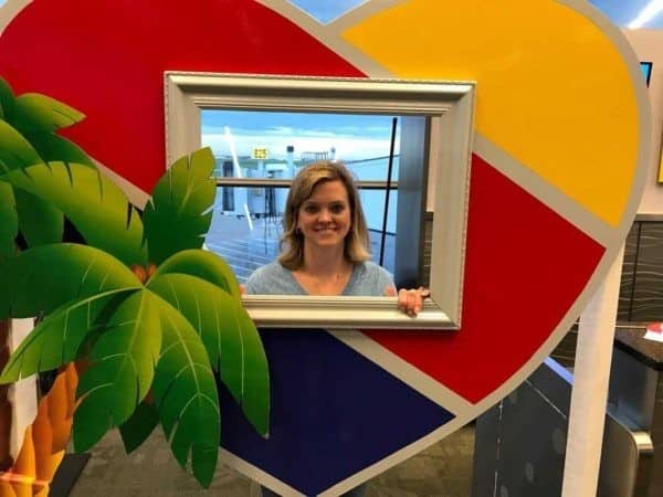 A woman standing in front of a heart shaped frame.