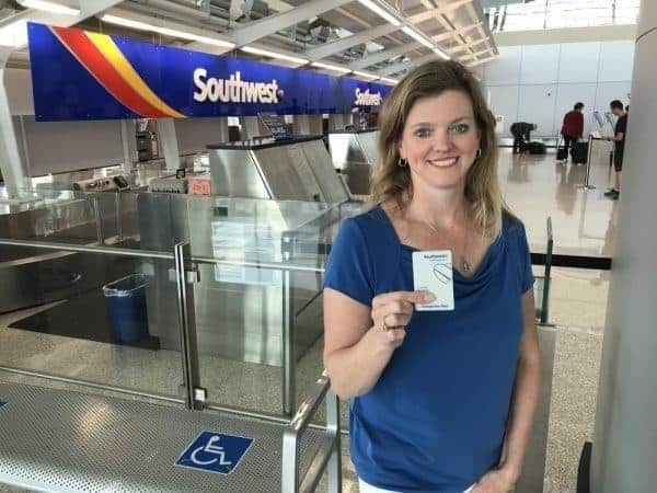 A woman holding a passport in front of an airport.